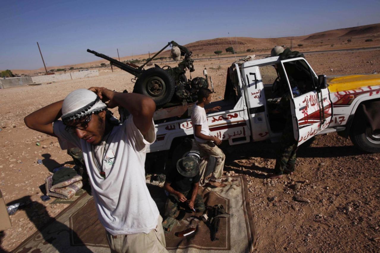 \'Anti-Gaddafi fighters prepare weapons to head towards the frontline in the north of the besieged city of Bani Walid September 11, 2011. REUTERS/Youssef Boudlal (LIBYA - Tags: POLITICS CIVIL UNREST)\