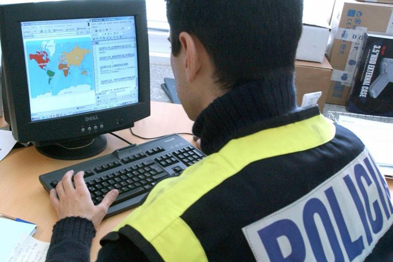 An undated photo made available by Spanish Police 28 January 2006, shows a Spanish policeman looking at a computer screen during an investigation against child pornography. Spanish police announced 28 January that six people were arrested after 62 interne