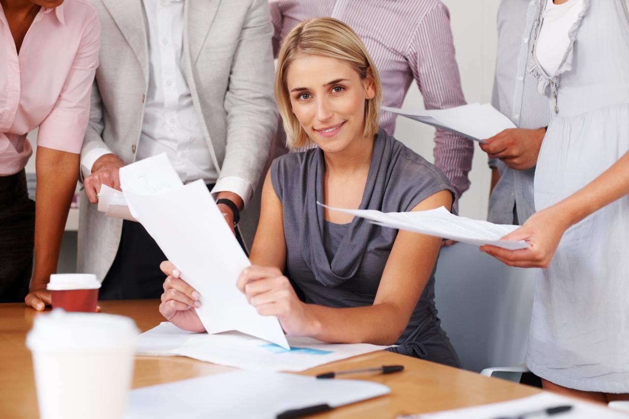 Happy woman with team working with documents at meeting