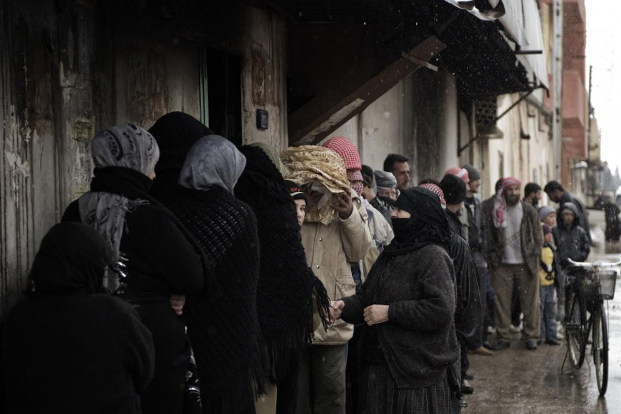 'Syrians queue for bread outside a bakery in Qusayr, 15 kms (nine miles) from Homs, on March 1, 2012. Syrian rebels were still holding out more than 24 hours into a ground assault by regime forces aga