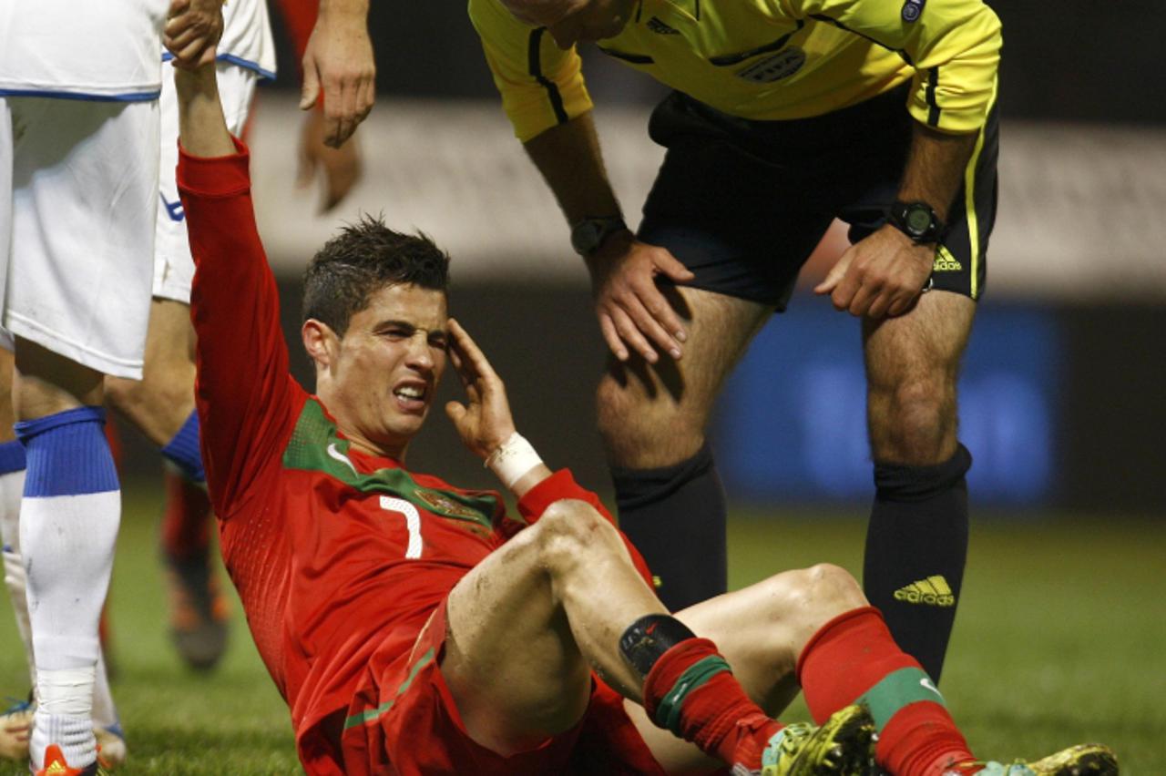 'Cristiano Ronaldo of Portugal grimaces next to referee Howard Webb after being tackled during the Euro 2012 play-off first leg qualifying soccer match against Bosnia in the town of Zenica November 11