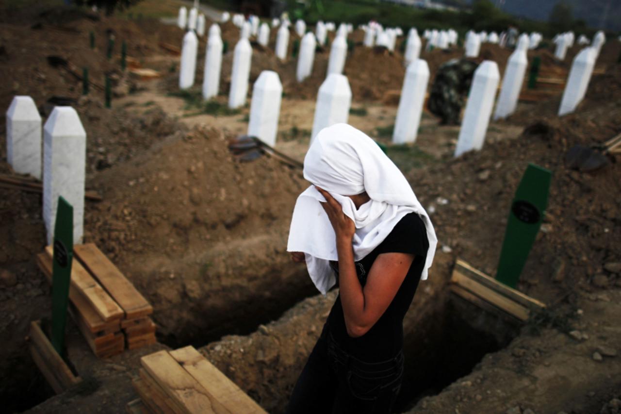 'A Bosnian Muslim woman cries near a new open grave with the coffin of her relative, which was prepared for a mass burial at the Memorial Center in Potocari, near Srebrenica July 10, 2012. The bodies 