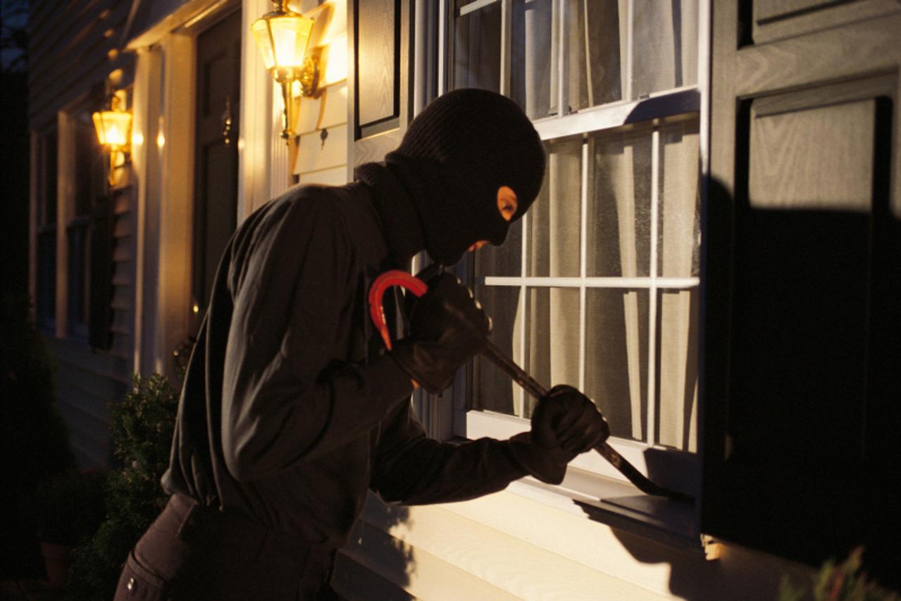 Burglar trying to pry open window on house