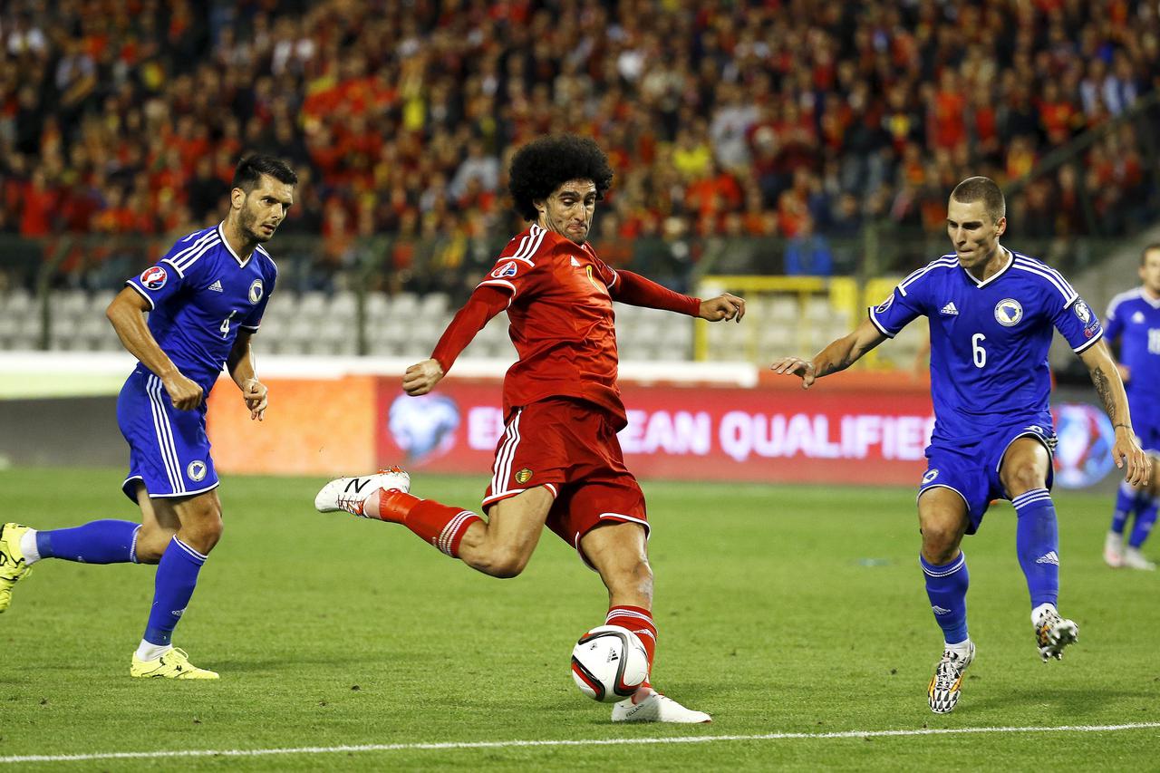 Belgium's Marouane Fellaini (C) kicks the ball past Bosnia's Emir Spahic (L) and Ognjen Vranjes during their Euro 2016 qualification match at the King Baudouin stadium in Brussels, Belgium September 3, 2015. REUTERS/Yves Herman
