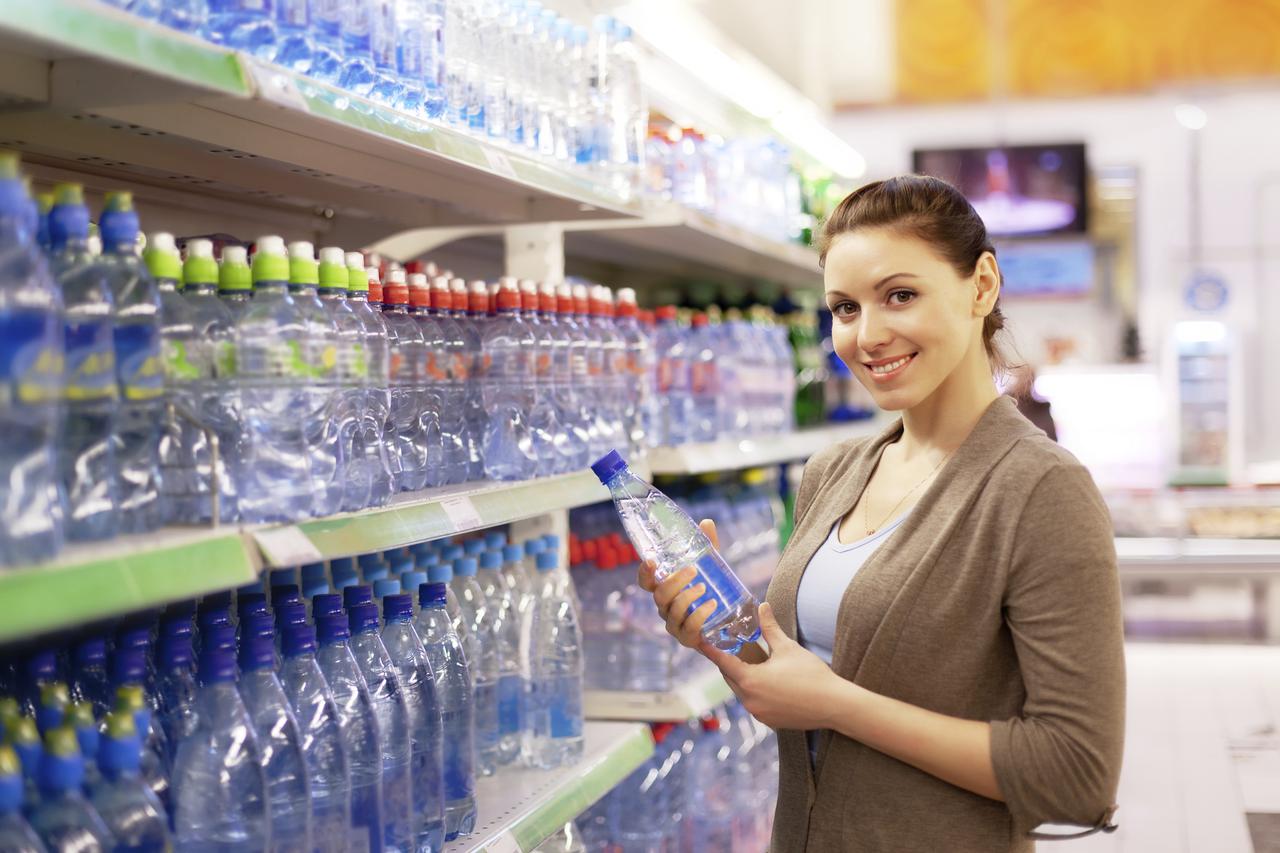 The woman buys a water bottle in shop
