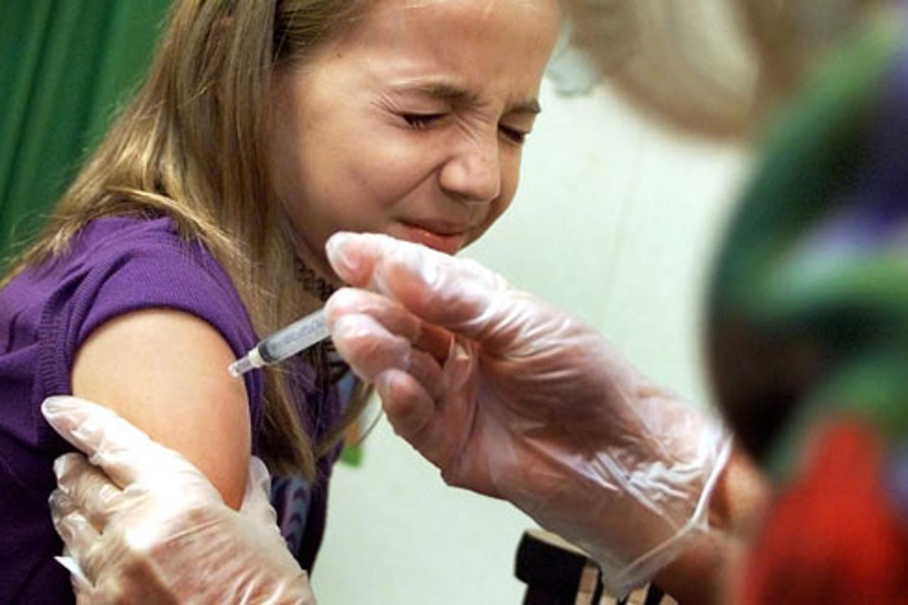 Orange County Register photo by Bruce Chambers - vaccine.p082801.bbc.2.jpg -Parkview Elemenmtary sixth grader May Kabartay, 11, winces, left, as she gets an immunization shot from registered nurse Riva Apodaca, right,  in preparation for the new school ye