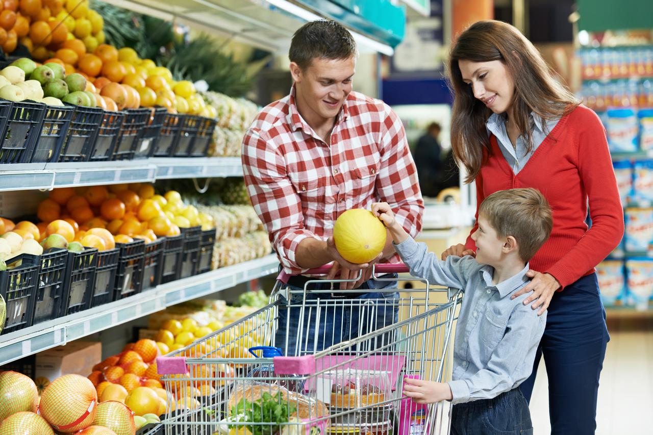 woman with man and child choosing melon fruit during shopping at vegetable supermarket