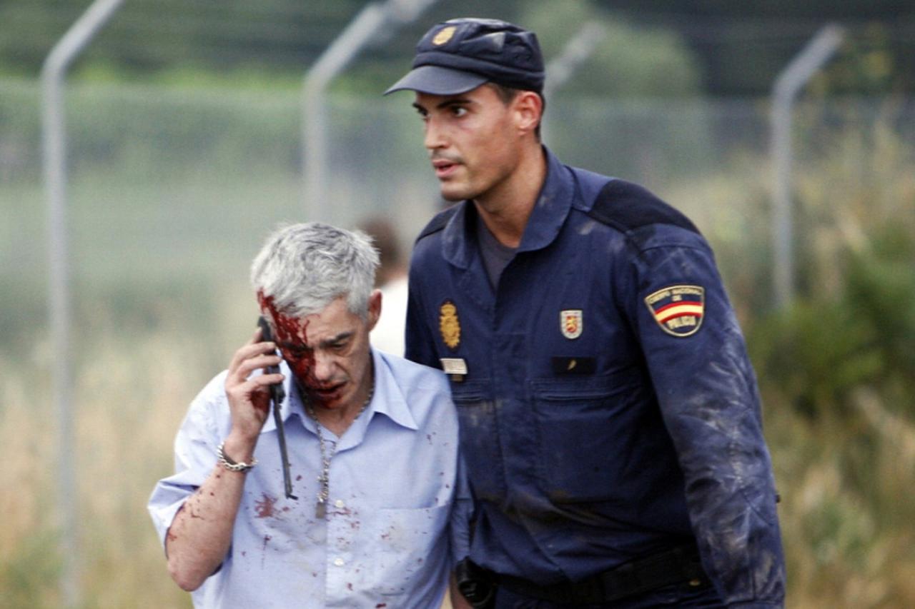 'An injured man, identified by Spanish newspapers El Pais and El Mundo as the train driver Francisco Jose Garzon, is helped by a policeman after a train crashed near Santiago de Compostela, northweste