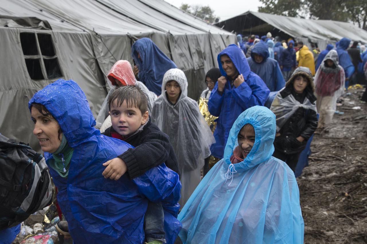 A child looks on as migrants walk to cross the border with Croatia near the village of Berkasovo, Serbia October 19, 2015. Thousands of migrants clamoured to enter European Union member Croatia from Serbia on Monday after a night spent in the cold and mud