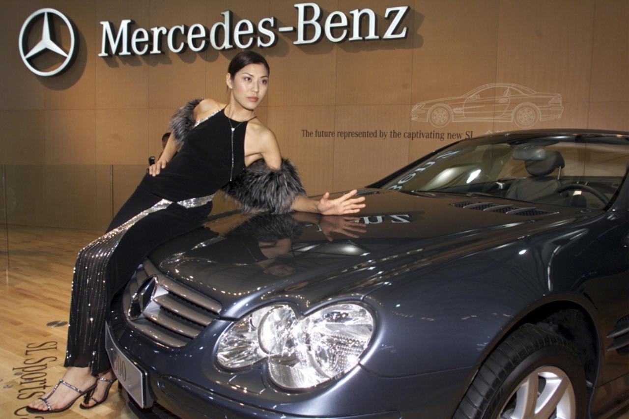 \'A Chinese model poses in front of a Mercedes SL-500 displayed at the Shanghai Motor Show in this December 9, 2001 file photo. Germany\'s Daimler on June 21, 2011 warned of increasing economic risks 