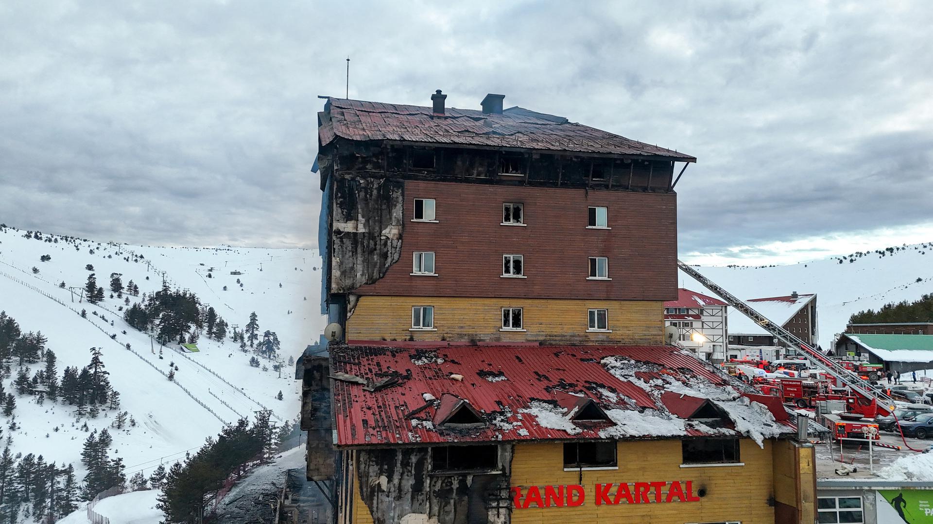 Nekoliko vatrogasnih vozila još uvijek se nalazi ispred uništene zgrade.
