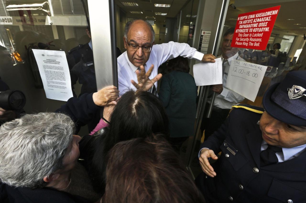 'A Laiki Bank manager tries to calm depositors waiting for the opening of the bank's branch in Nicosia March 28, 2013. Banks in Cyprus opened their doors on Thursday for the first time in almost two 