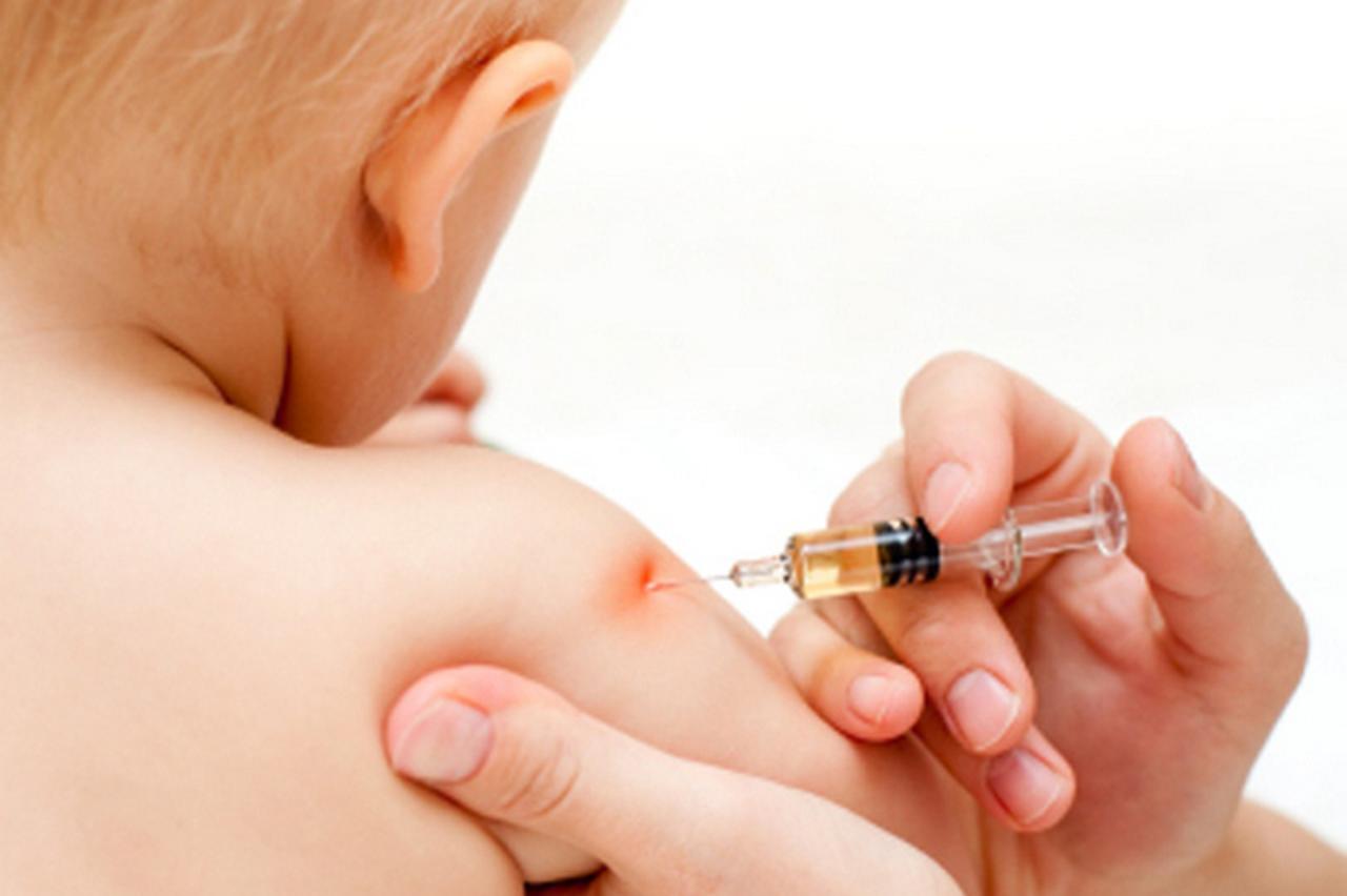 Doctor giving a child an intramuscular injection in arm, shallow DOF