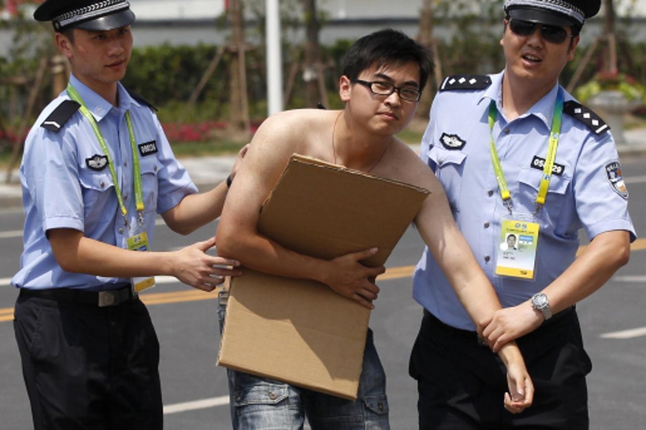 \'A man carrying a sign is detained by the police after he ran into a restricted area at the Oriental Sports Centre, venue for the 14th FINA World Championships, in Shanghai July 15, 2011. Shanghai wi