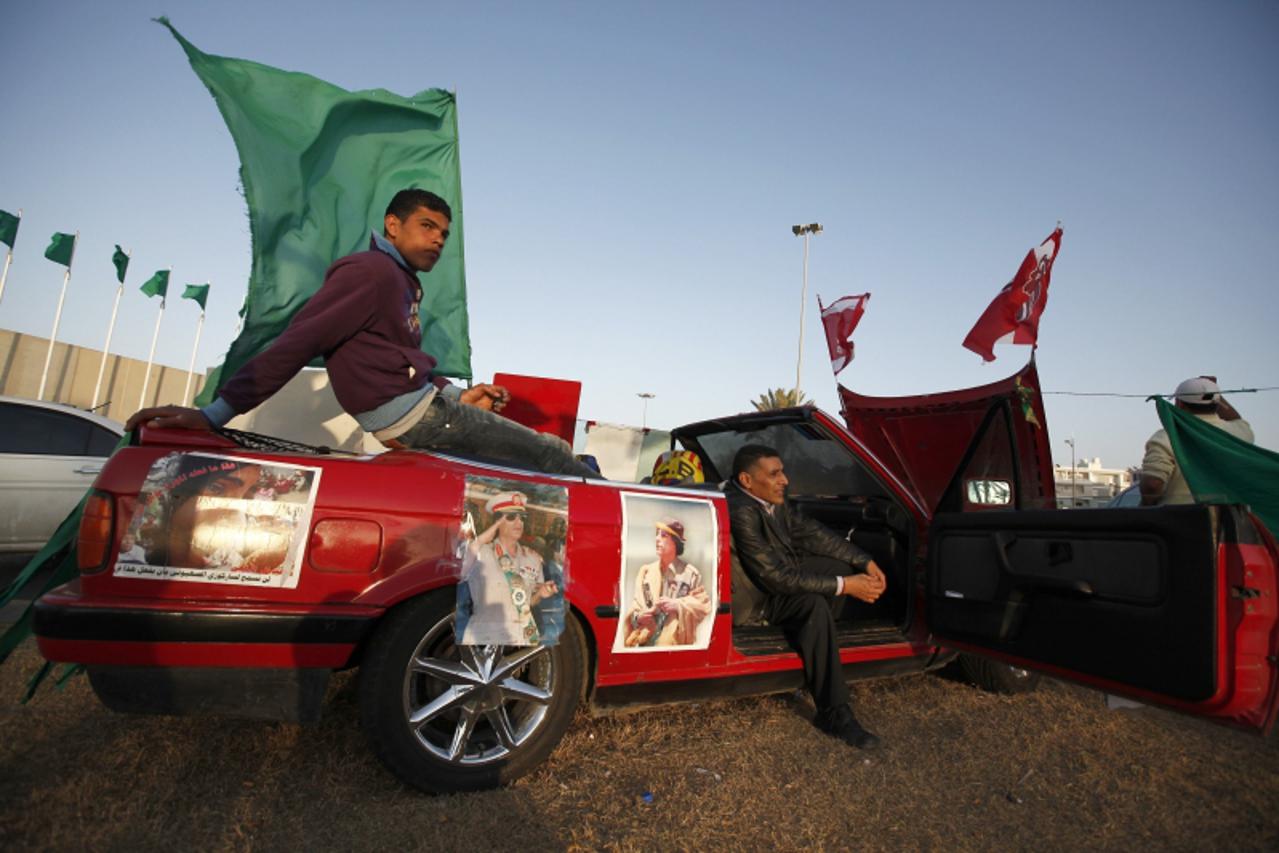 'Libyans loyal to Libya\'s leader Muammar Gaddafi sit in their car in front of Bab Al-Aziziyah, Gaddafi\'s heavily fortified compound, in Tripoli March 27, 2011. REUTERS/Zohra Bensemra (LIBYA - Tags: 