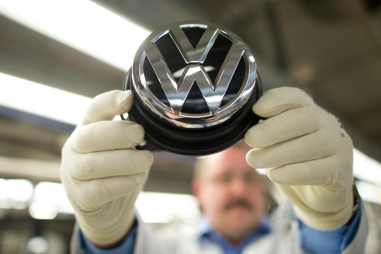 An employee holds a Volkswagen logo in the production street for the Golf VII at the Volkswagen plant in Wolfsburg, Germany, 25 February 2013. Photo: Julian Stratenschulte/DPA/PIXSELL