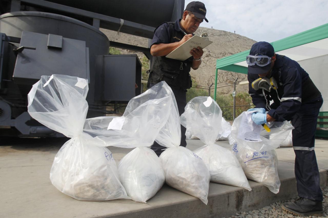 'Anti-narcotics workers display bags containing cocaine in front of an incinerator in Lima April 26, 2012. More than four tonnes of drugs, which includes cocaine, cocaine paste and marijuana, that wer