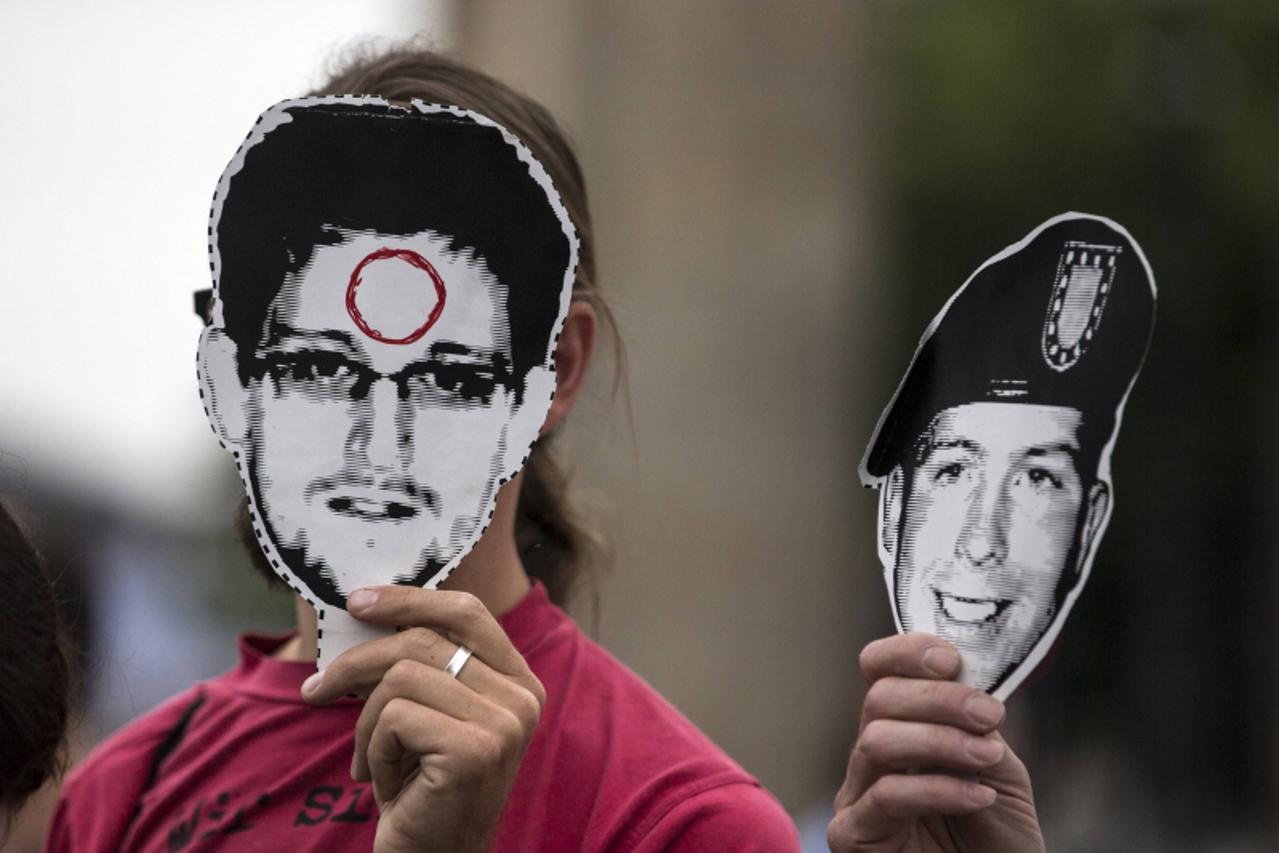 'People hold portraits of former U.S. spy agency contractor Edward Snowden (L) and U.S. Army Private First Class Bradley Manning in front of their faces during a protest in front Brandenburg Gate in B