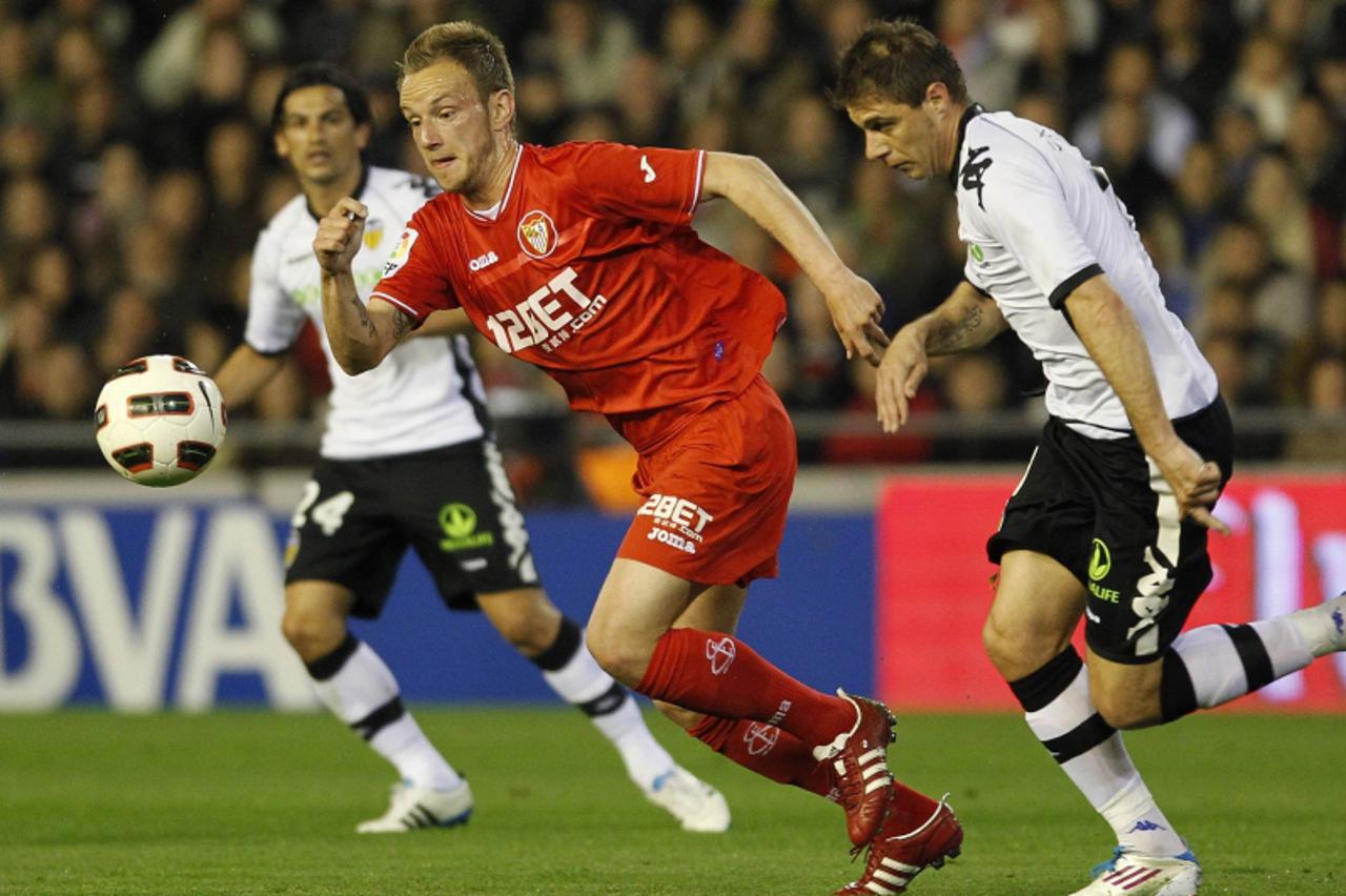 \'Sevilla\'s Ivan Rakitic (C) and Valencia\'s Joaquin Sanchez fight for the ball as Tino Costa watches during their Spanish first division soccer match at the Mestalla Stadium in Valencia, March 20, 2