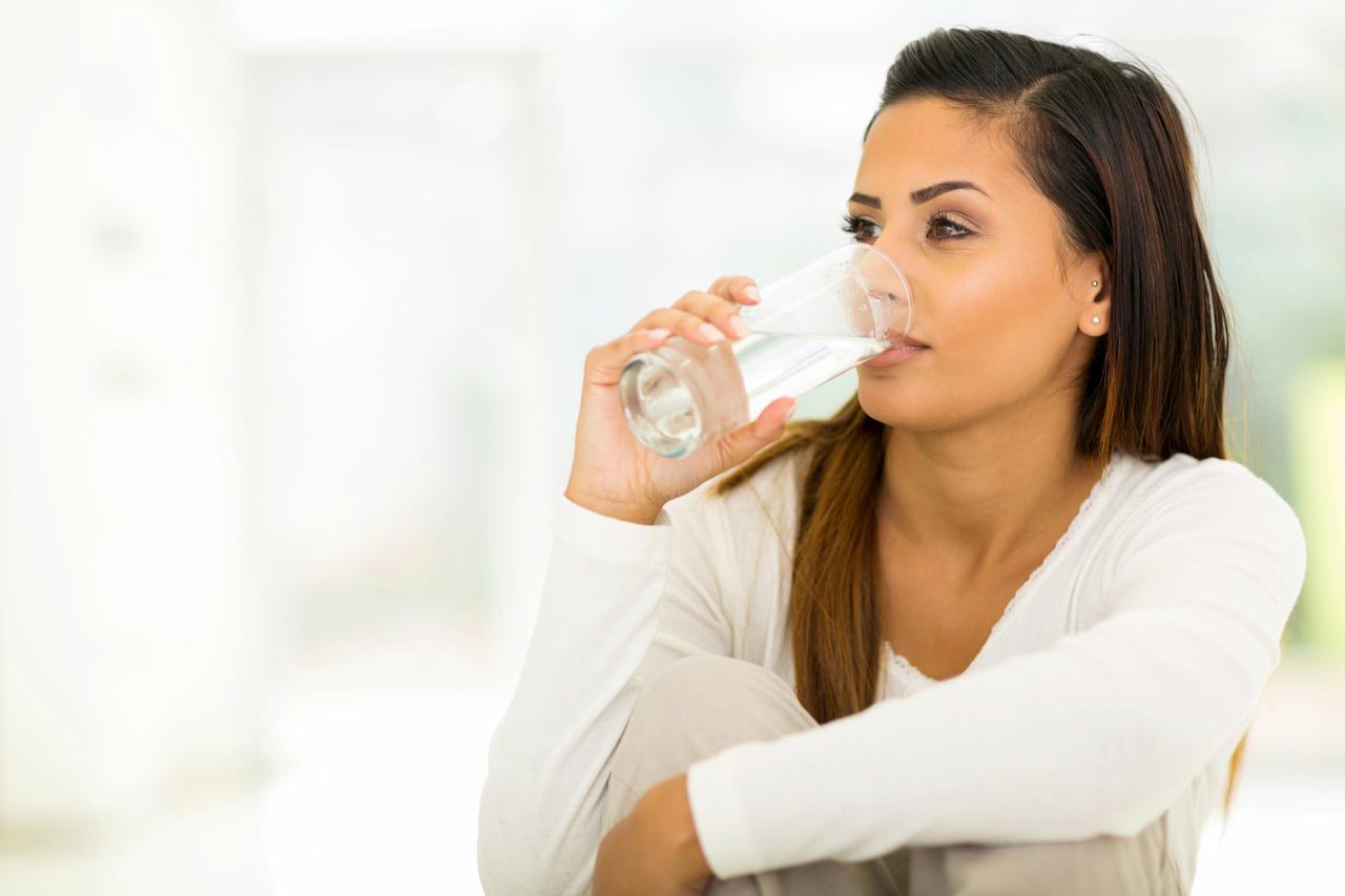 beautiful young woman drinking water in the morning