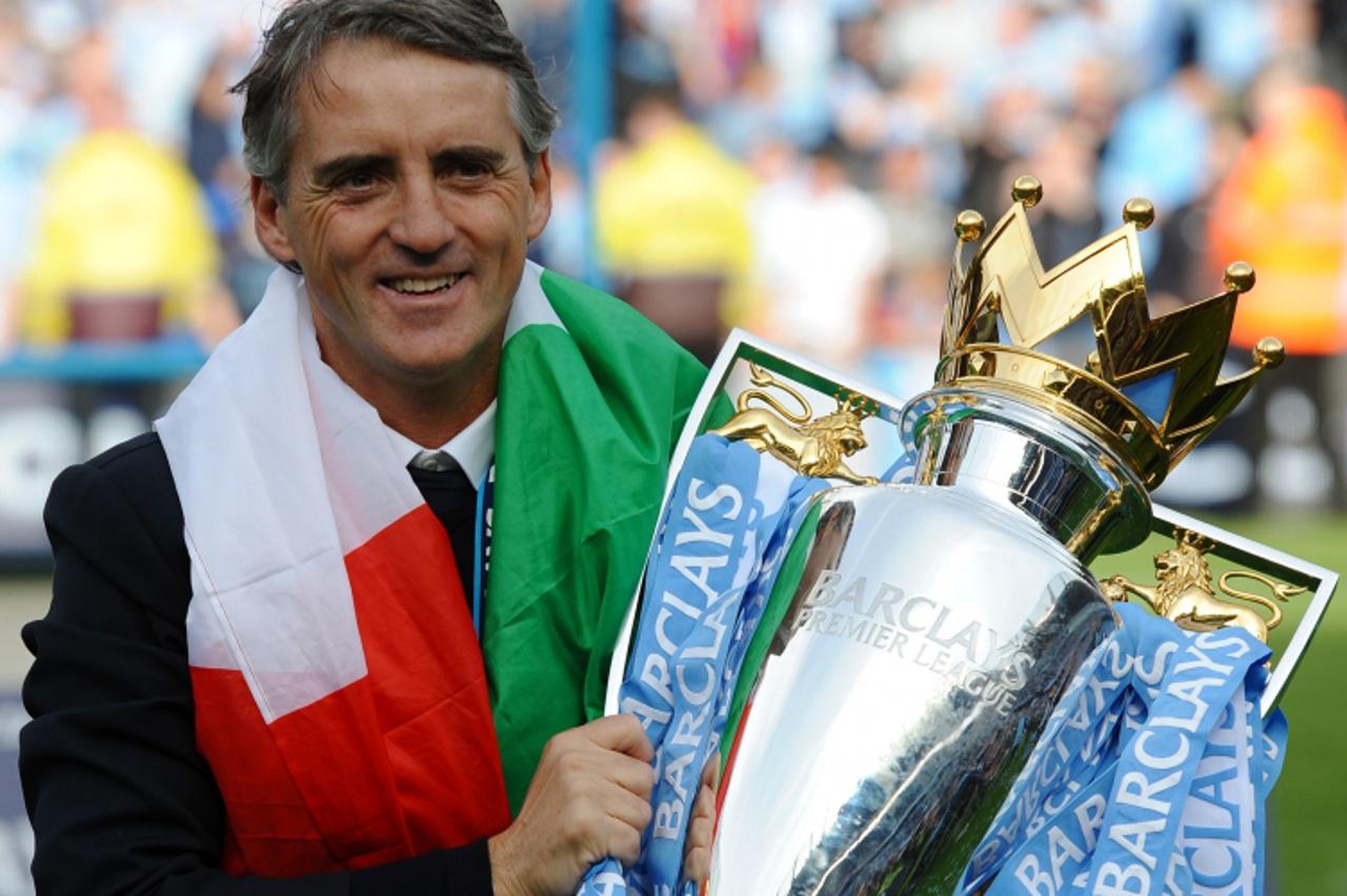 'Manchester City\'s Italian manager Roberto Mancini celebrates on the pitch with the Premier League trophy after their 3-2 victory over Queens Park Rangers in the English Premier League football match
