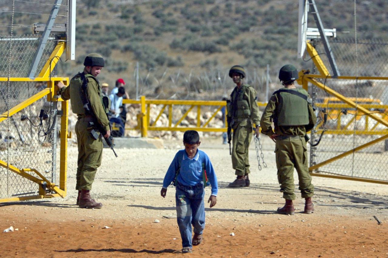 'palestina izrael Israeli soldiers open a gate in the security fence, built by Israel to seperate Israel from the West Bank, for a Palestinian boy returning from school to his village near the West Ba