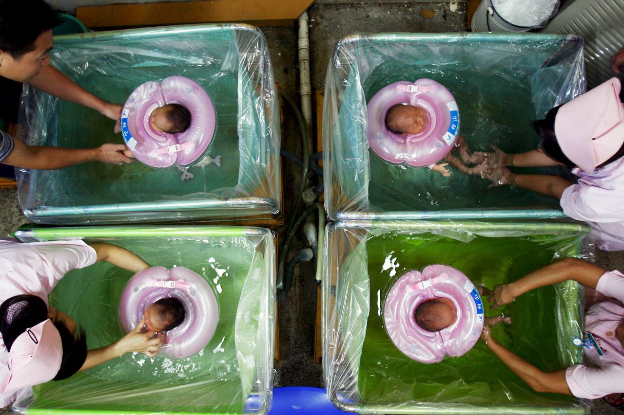 Newborn babies are given baths by a parent and nurses at a hospital in Wuhan, capital of central China's Hubei province, in this August 19, 2006 file photo.  China will ease family planning restrictions to allow all couples to have two children after deca