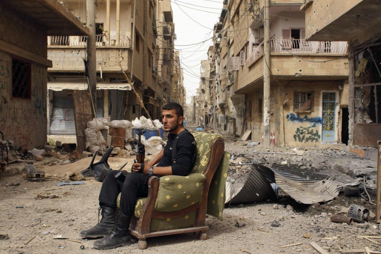 'A member of the Free Syrian Army holds his weapon as he sits on a sofa in the middle of a street in Deir al-Zor April 2, 2013. Picture taken April 2, 2013. REUTERS/ Khalil Ashawi (SYRIA - Tags: CONFL
