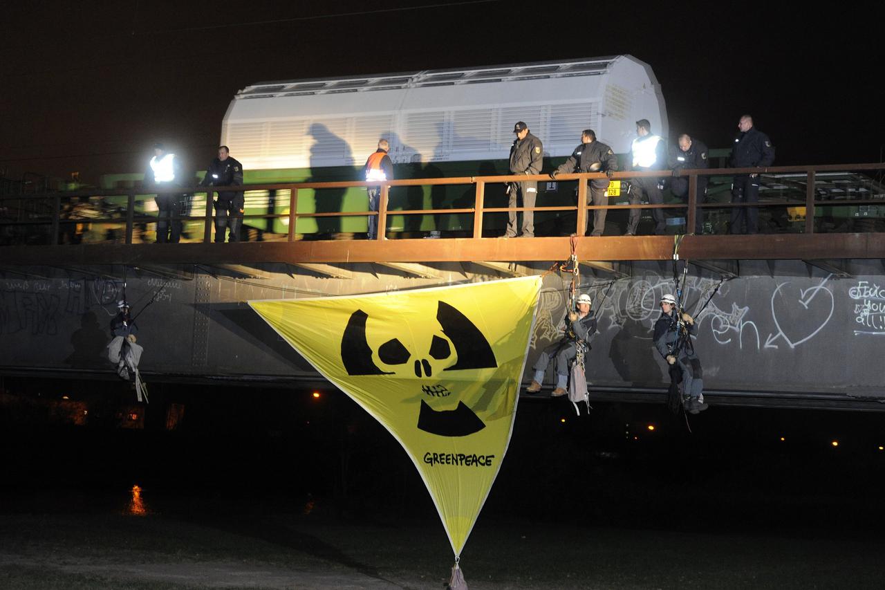 A train with eleven CASTORs drives out of the train station in Kehl, Germany, 06 November 2010. Greenpeace activists hang underneath the bridge and demonstrate with a banner. The CASTOR transport heads from the French nuclear reprocessing facility in La H