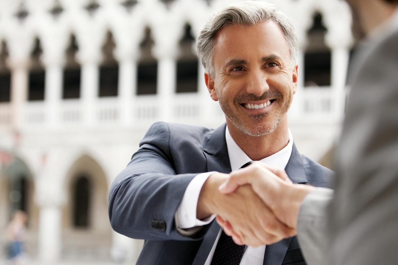 Smiling businessmen shaking hands at sidewalk cafe