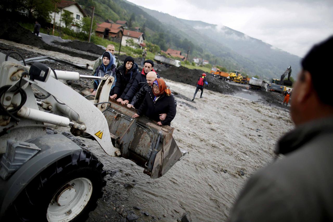 People are carried by a front loader as they evacuate from their flooded houses in Topcic Polje, near Zepce May 16, 2014. The heaviest rains and floods in 120 years have hit Bosnia and Serbia, killing five people, forcing hundreds out of their homes and c