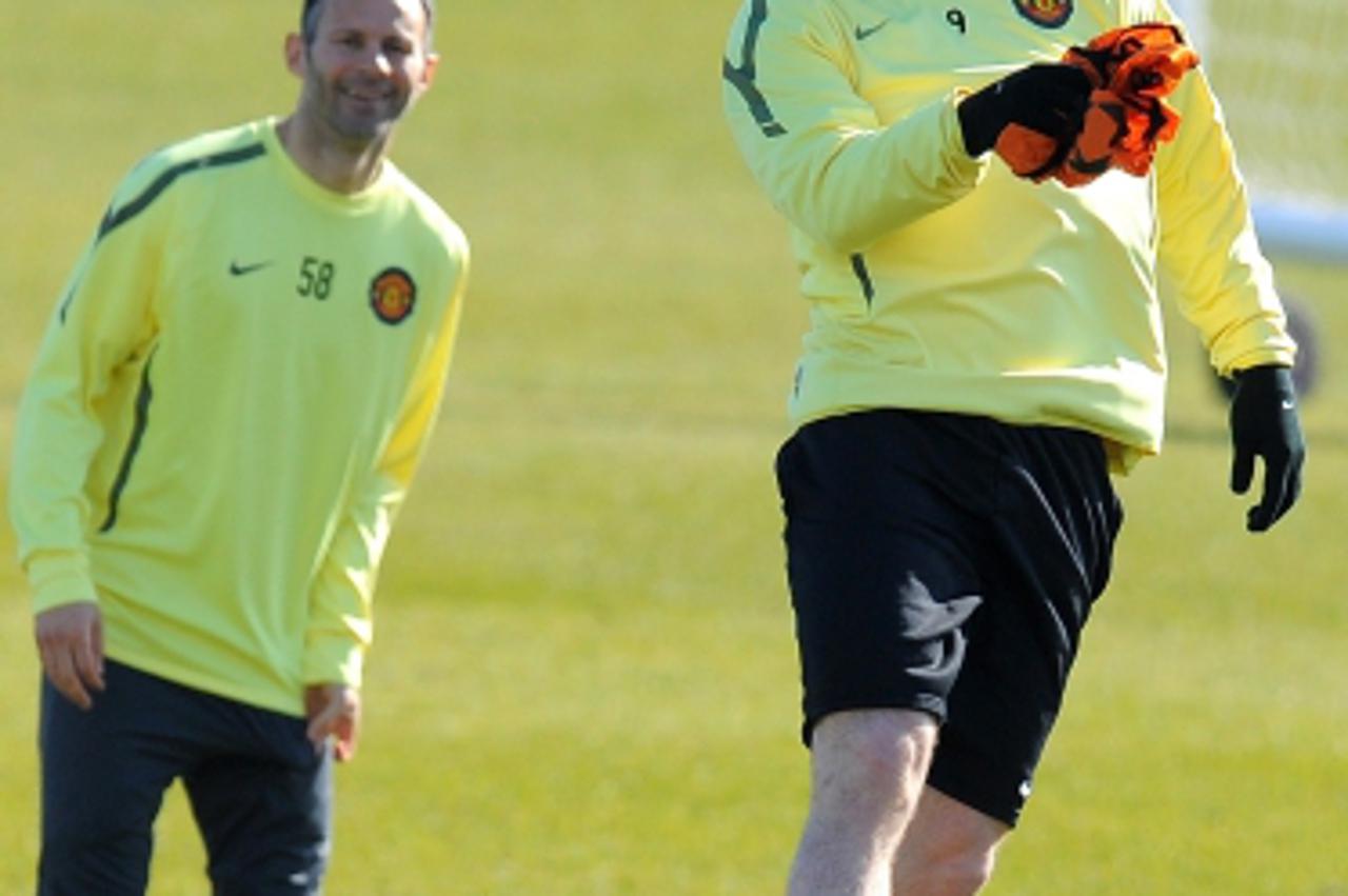 'Manchester United\'s English forward Wayne Rooney (R) watched by Manchester United\'s Welsh midfielder Ryan Giggs wins a header during a training session at the Carrington complex in Manchester, nort