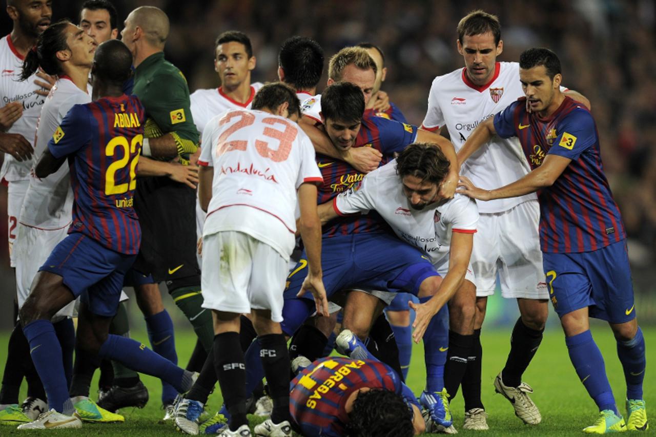 'Barcelona\'s forward Cesc Fabregas (C-down) falls on the ground after he was attacked by Sevilla\'s Malian forward Frederic Kanoute during the Spanish League football match between Barcelona and Sevi