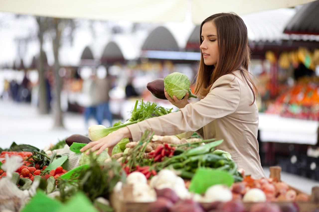 Young woman picking vegetables at farmer's market