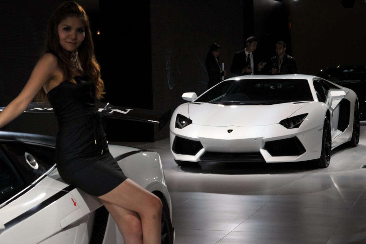 'A model poses in front of a Lamborghini Aventador at the Top Marques Macau car show in Macau on November 25, 2011.  The Top Marques Macau car show, which is orginally from Monaco, showcases a star st