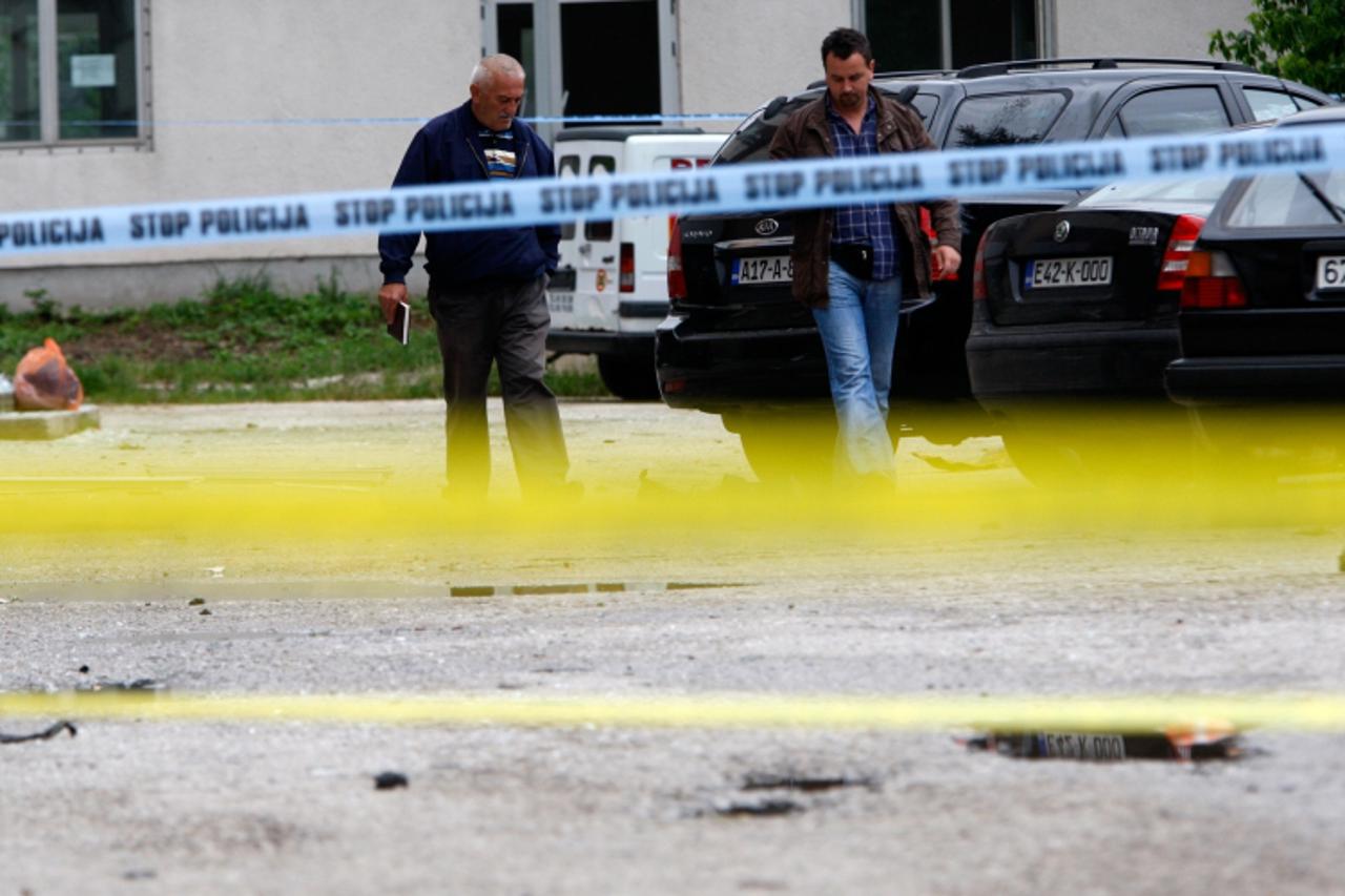 \'Police investigators look at damaged vehicles on parking lot in front of a police station in the central Bosnian town of Bugojno on June 27, 2010. A powerful blast ripped through the police station 