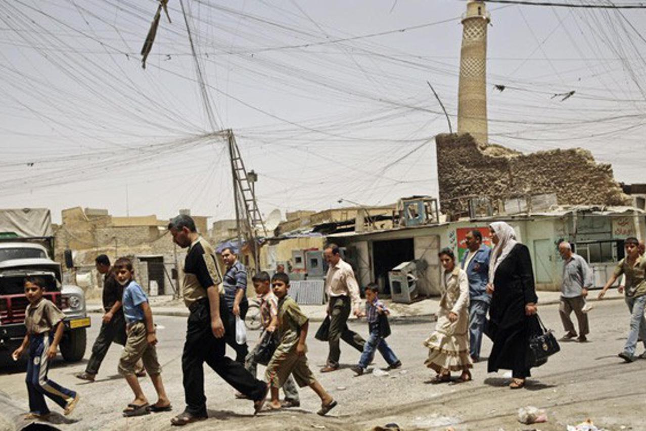 In this Monday, June 8, 2009 file photo, residents walk past the al-Hadba minaret in a busy market area in Mosul, Iraq.