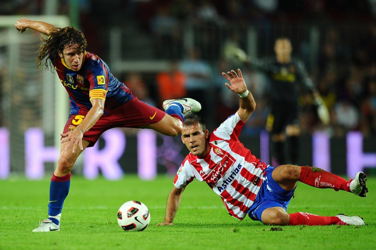 \'Barcelona\'s captain Carles Puyol (L) vies with Sporting Gijon\'s Croatian forward Mate Bilic (R) during the Spanish League football match Barcelona against Sporting Gijon on September 22, 2010 at t