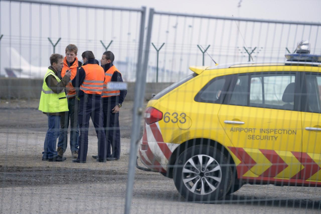'Airport security guards and officials stand near an entrance to the tarmac at Zaventem international airport near Brussels February 19, 2013. Robbers dressed as police and armed with machineguns have