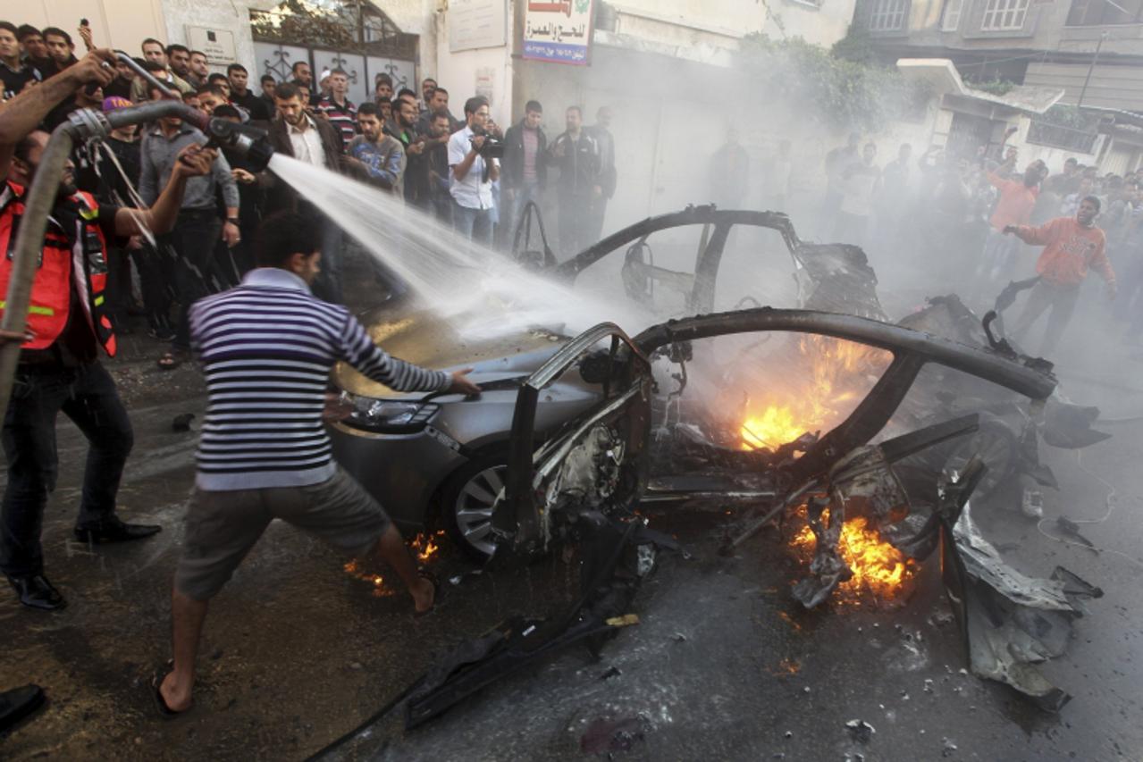 'Palestinians help extinguish the fire after an Israeli air strike on the car of Hamas\'s top commander in Gaza City November 14, 2012. An Israeli official said on Wednesday the assassination of Hamas