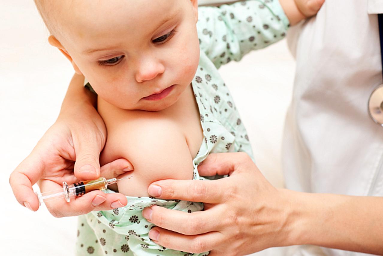 Doctor giving a child an intramuscular injection in arm, shallow DOF