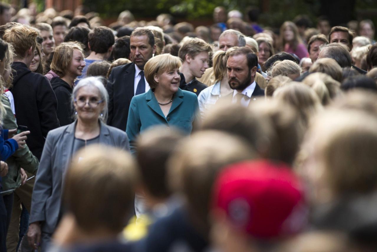 'German Chancellor Angela Merkel (C) arrives for a visit to the Heinz Schliemann grammar school in Berlin August 13, 2013. Merkel on Tuesday delivered a guest history lecture on the erection of the Be