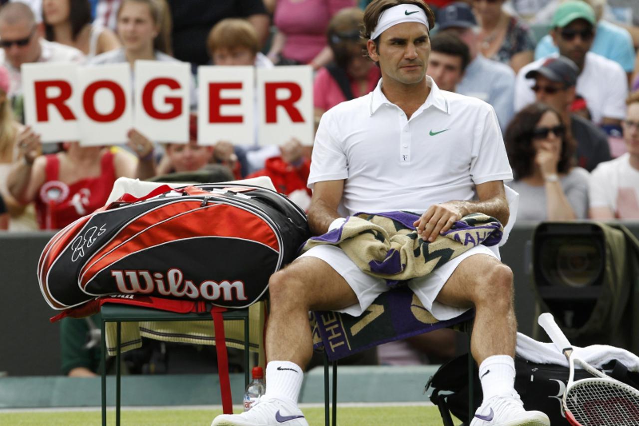 'Roger Federer of Switzerland sits on his seat during his men\'s singles tennis match against Albert Ramos of Spain at the Wimbledon tennis championships in London June 25, 2012.              REUTERS/