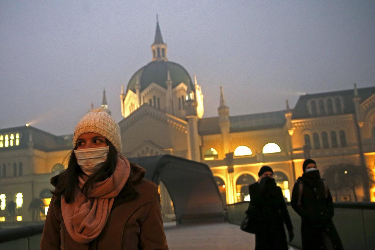 Women wearing masks walk in front of academy of fine arts as smog blankets Sarajevo, Bosnia and Herzegovina December 23, 2015. With severe air pollution affecting the city nestled among the mountains, the authorities have declared the first level of prepa