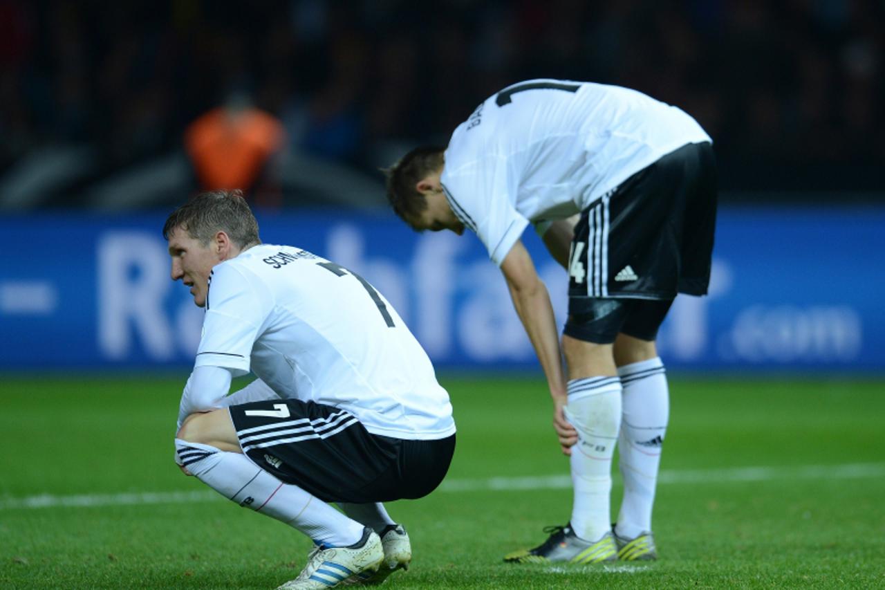 'German midfielder Bastian Schweinsteiger (L) and defender Holger Badstuber  react after the FIFA World Cup 2014 qualifying match Germany vs Sweden on October16, 2012 in Berlin. The match ended 4-4 in