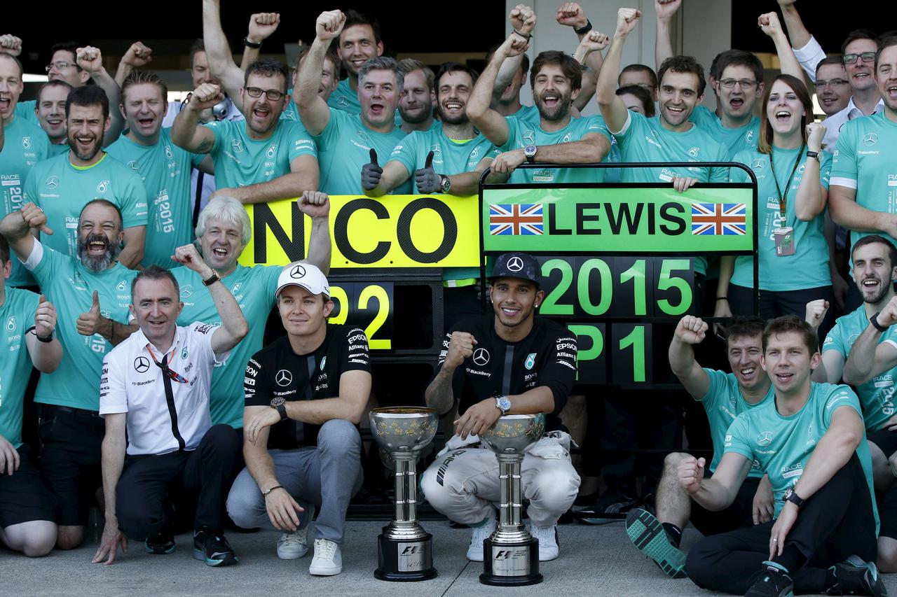 Mercedes Formula One driver Lewis Hamilton of Britain (front C) and teammate driver Nico Rosberg of Germany pose with their trophies and members of the Mercedes team as they celebrate their first and second places respectively at the team garage after the