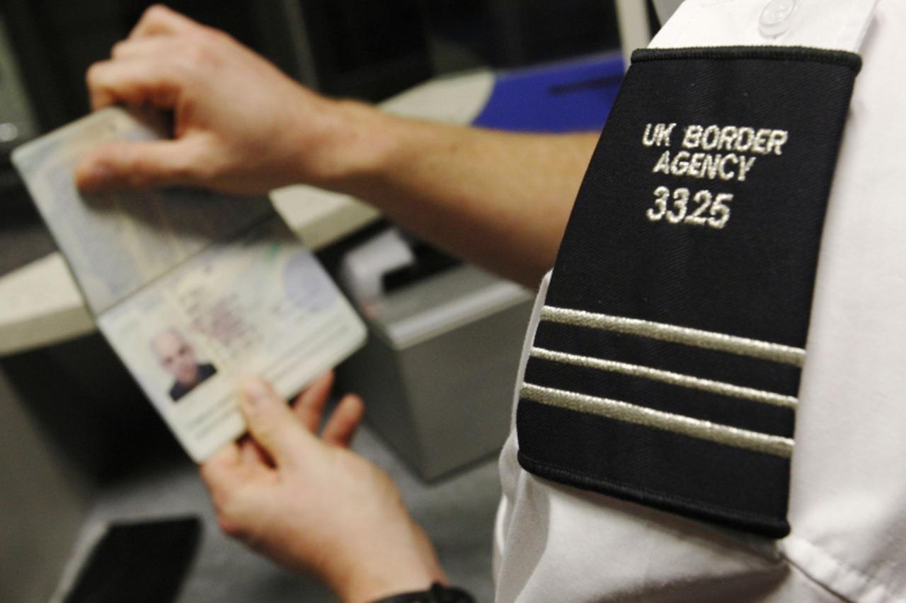 \'A UK Border Agency worker poses with a passport during a demonstration of the new facial recognition gates at the North Terminal of Gatwick Airport near London, November 23, 2009. The gates can be u