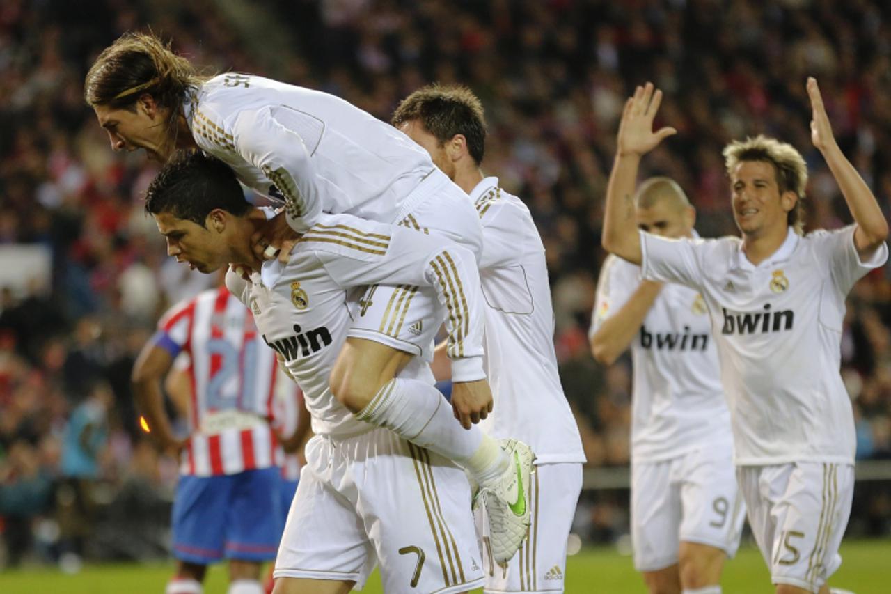 'Real Madrid\'s Portuguese forward Cristiano Ronaldo (L) celebrates with teammates after scoring his second goal during the Spanish league football match Atletico Madrid against Real Madrid at the Vic