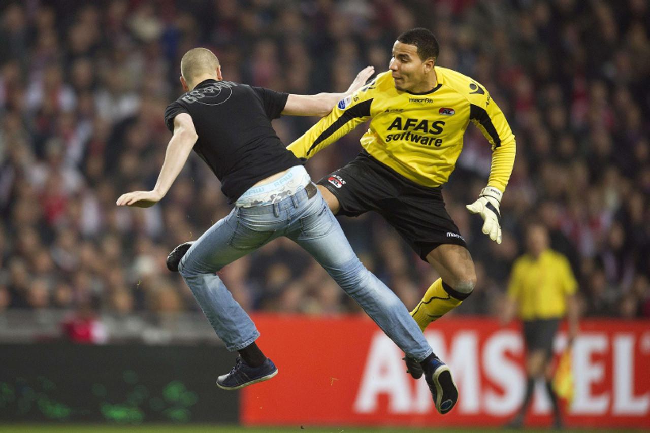 'Goalkeeper Esteban of AZ Alkmaar (R) kicks a man who attacked him from behind during their football cup match against Ajax at the Arena stadium in Amsterdam, on December 21, 2011. AZ Alkmaar cancelle