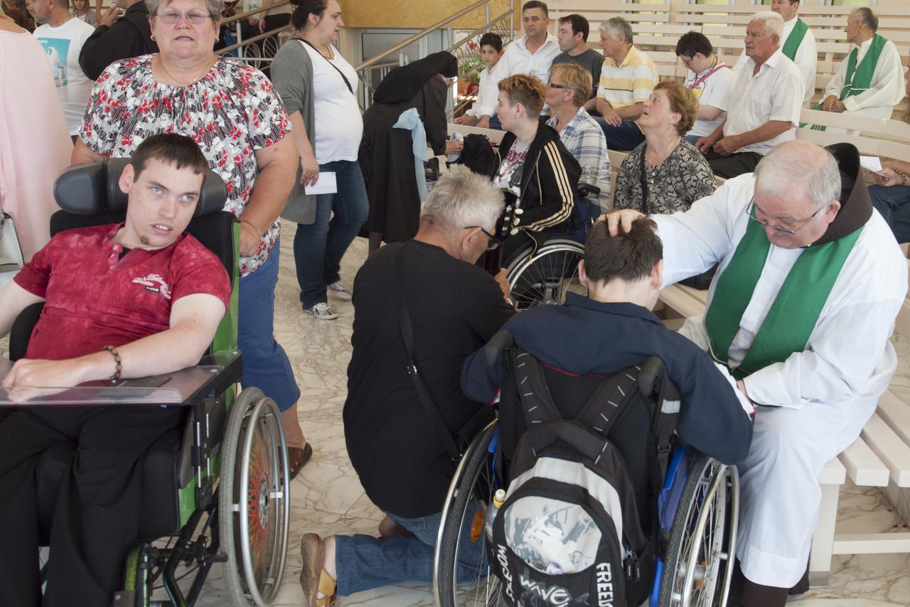 Svećenik ispovjeda jednu osobu s invaliditeto. Medjugorje, 12.06.2016.Snimio.marijan Sivrić
